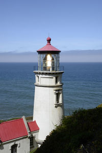Heceta head lighthouse on a sunny day with pacific ocean background.