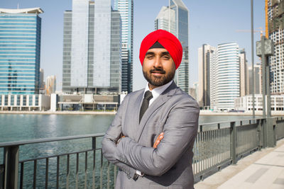 Portrait of businessman wearing turban standing against river