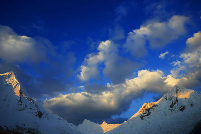 Low angle view of snow covered mountain against blue sky