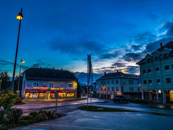 Street amidst buildings against sky at dusk