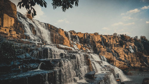 Scenic view of waterfall against sky