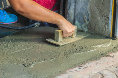 Midsection of man working on concrete wall