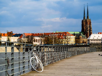 Abandoned white retro bicycle on city wooden pier with old town city view. wroclaw, poland