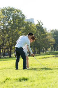 Full length of couple playing golf on field