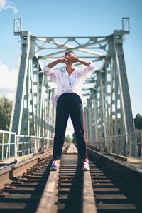 Full length of woman standing on railroad tracks against sky