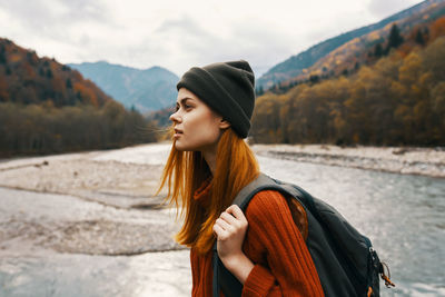 Beautiful young woman looking away while standing on mountain