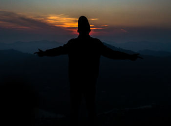 Silhouette woman standing on mountain against sky during sunset