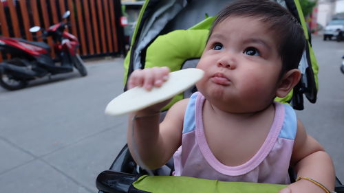 Close-up of cute boy holding food while sitting in baby stroller