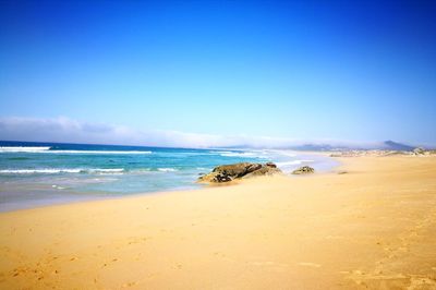 Scenic view of beach against blue sky
