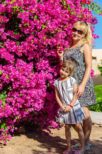 Full length of smiling young woman standing by plants