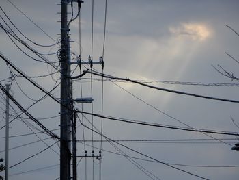 Low angle view of electricity pylons against sky