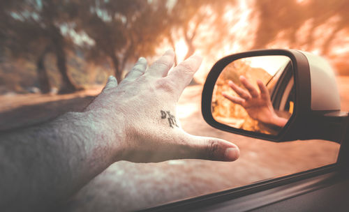 Close-up of man hand on side-view mirror