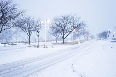 Snow covered road in city against sky