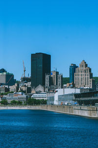 Buildings by sea against blue sky