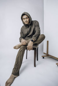 A young asian man in a hoodie sitting on a white background