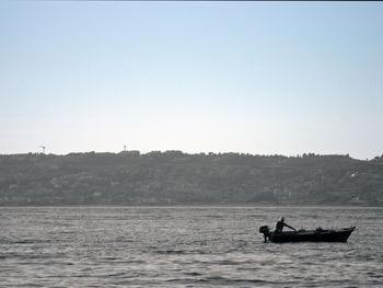 Man on boat in sea against clear sky