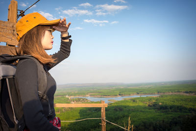 Side view of woman standing on field against sky