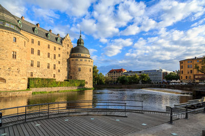  the castle by river against cloudy sky