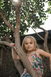 Girl on tree looking at camera