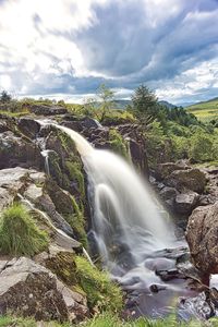 Scenic view of waterfall against sky