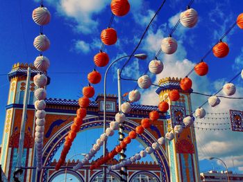 Low angle view of lighting equipment hanging against blue sky