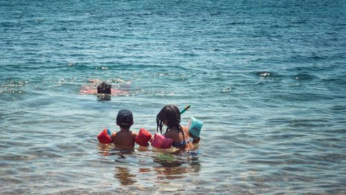 Children looking at father swimming in sea