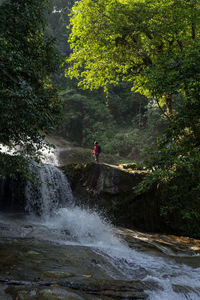 A male traveller exploring the beautiful of rainforest waterfall. 