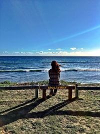 Rear view of woman standing on beach against clear sky