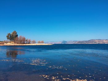 Scenic view of lake against clear blue sky
