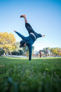 Low angle view of man jumping on field against sky