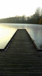 Boardwalk over lake against clear sky