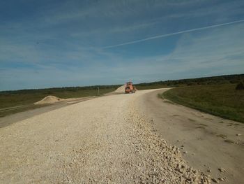 Dirt road on landscape against sky