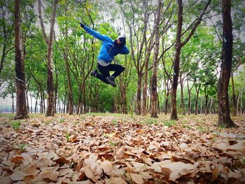 Man jumping amidst trees on field