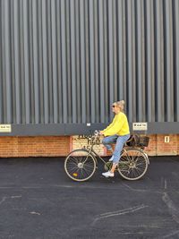 Man with bicycle on road against wall