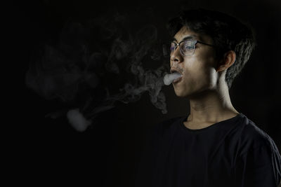 Portrait of young man standing against black background