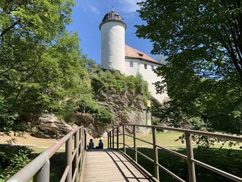 Footbridge over footpath amidst trees and buildings