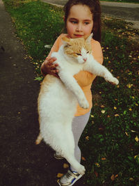 Portrait of young woman with cat on plant