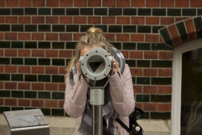 Woman looking through coin-operator binoculars