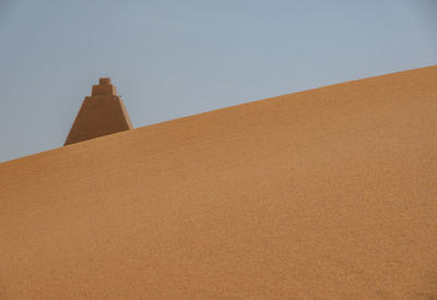 Tip of a pyramid behind a dune in sudan, sahara