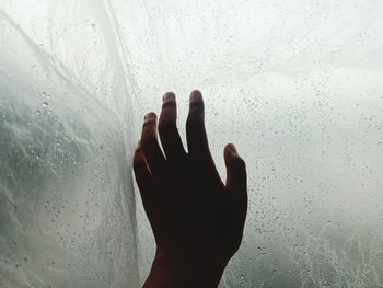 Cropped hand touching wet glass