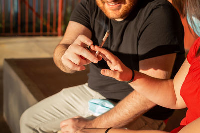 Midsection of man giving marijuana joint outdoors