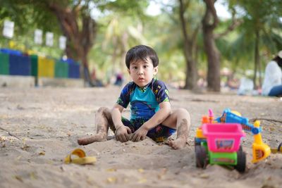 Portrait of boy playing with toy sitting on sand