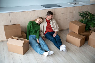 Tired couple man woman dreaming about life in new apartment resting sitting on floor.
