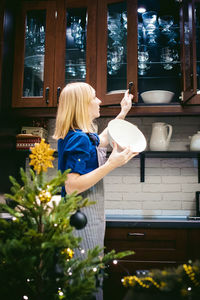 Woman taking bowl from kitchen cabinet