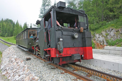 Engineers in steam train at railroad station platform