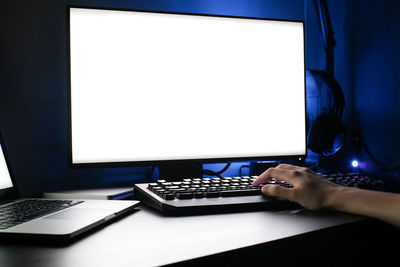 Cropped hand of woman using computer in darkroom