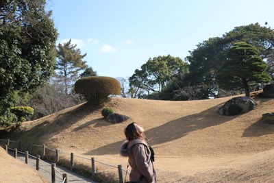 Rear view of woman with umbrella against sky