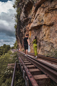 Couple holding hands while walking on railroad tracks