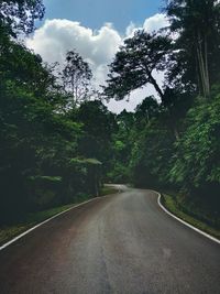 Empty road amidst trees against sky