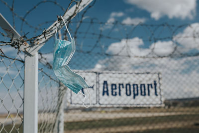 Close-up of text on fence against sky